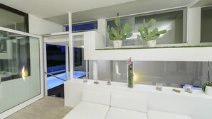 A modern interior with a white sofa, a glass partition, and potted plants on shelves. - Villa Katy (Bardolino)