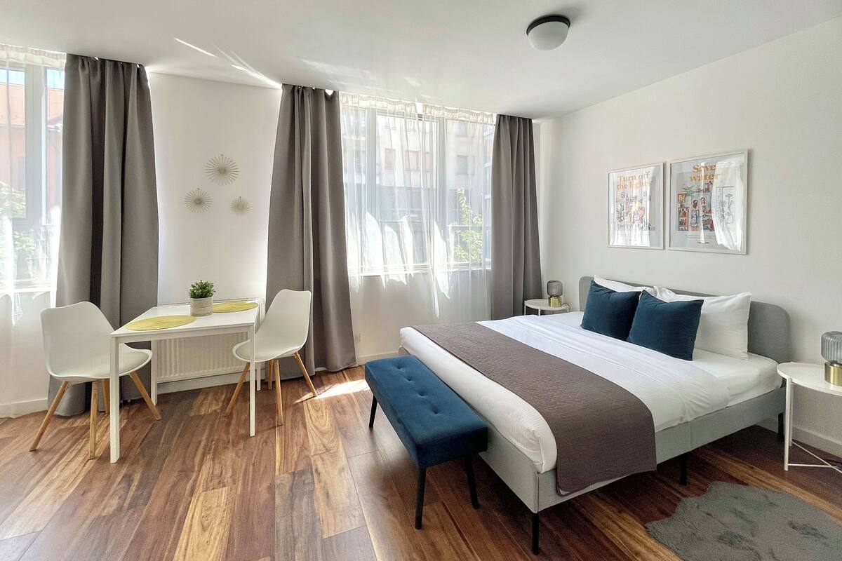 Une chambre moderne avec un grand lit, un bureau, deux chaises et un banc.