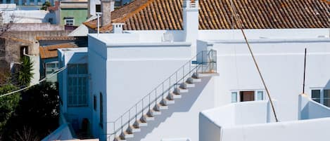 A white building with a tiled roof and a staircase leading to an upper level.