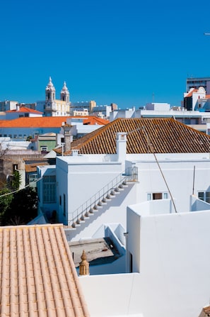 A white building with a tiled roof and a staircase leading to an upper level.