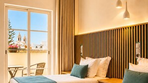 Habitación de hotel con dos camas, un balcón con vistas y una pared de paneles de madera.