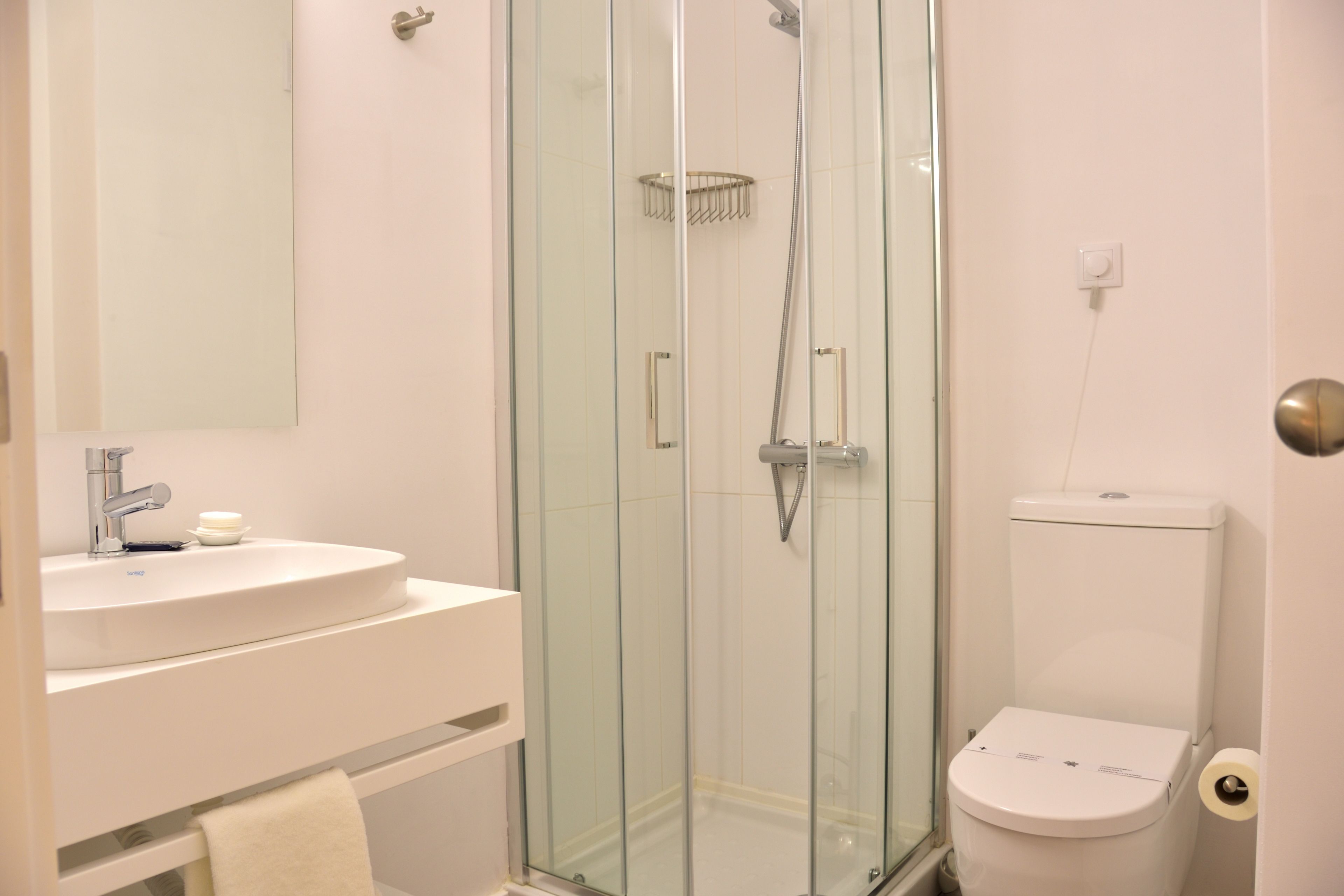 Une salle de bain avec une douche à parois de verre, un lavabo blanc et des toilettes.