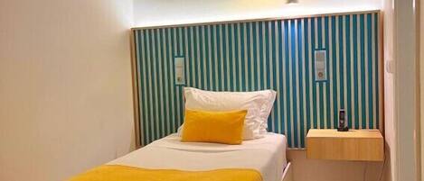 A bedroom with a bed, bedside table, and a wall-mounted light fixture.