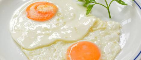 Two sunny-side-up eggs on a white plate with a blue rim.
