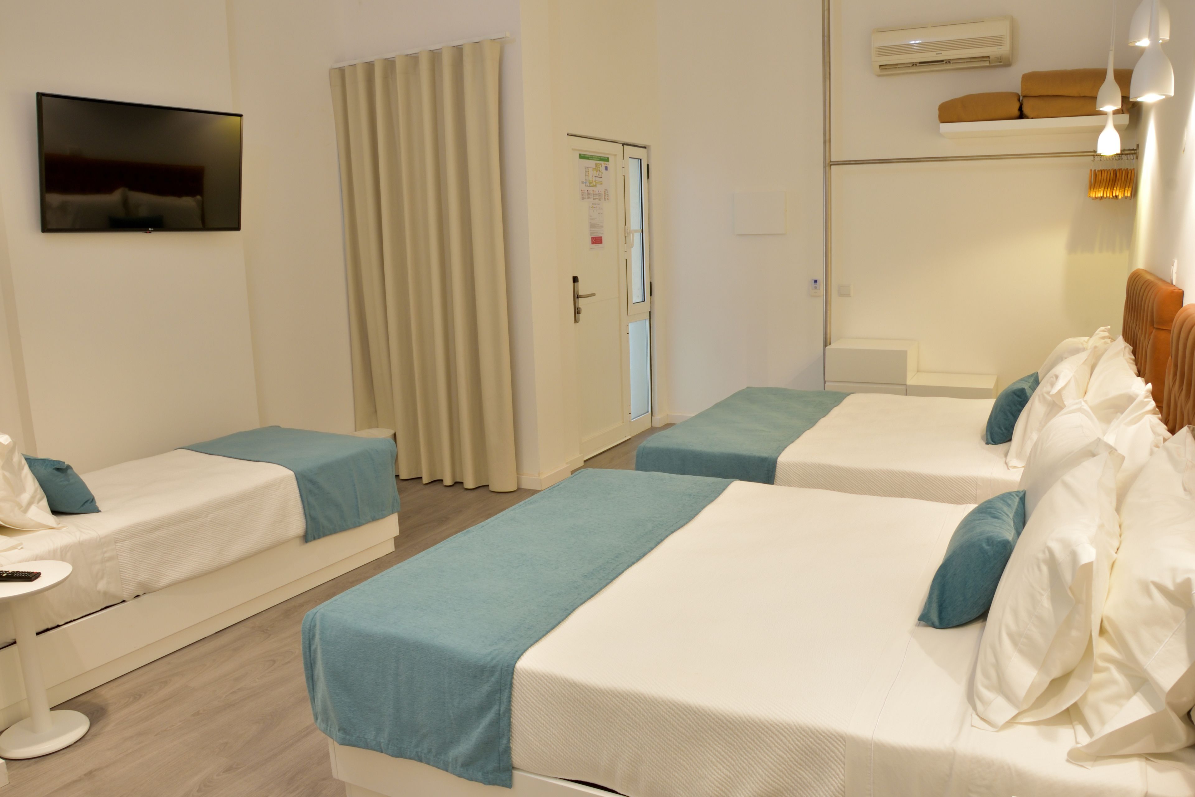 A hotel room with two single beds, a TV, a desk, and a door.