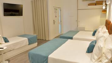 Habitación de hotel con dos camas individuales, televisión, escritorio y puerta.