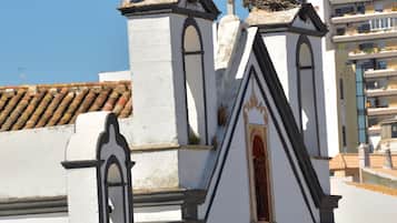 A building with a white facade and a tiled roof. There are two bird nests on the roof, each with two birds.