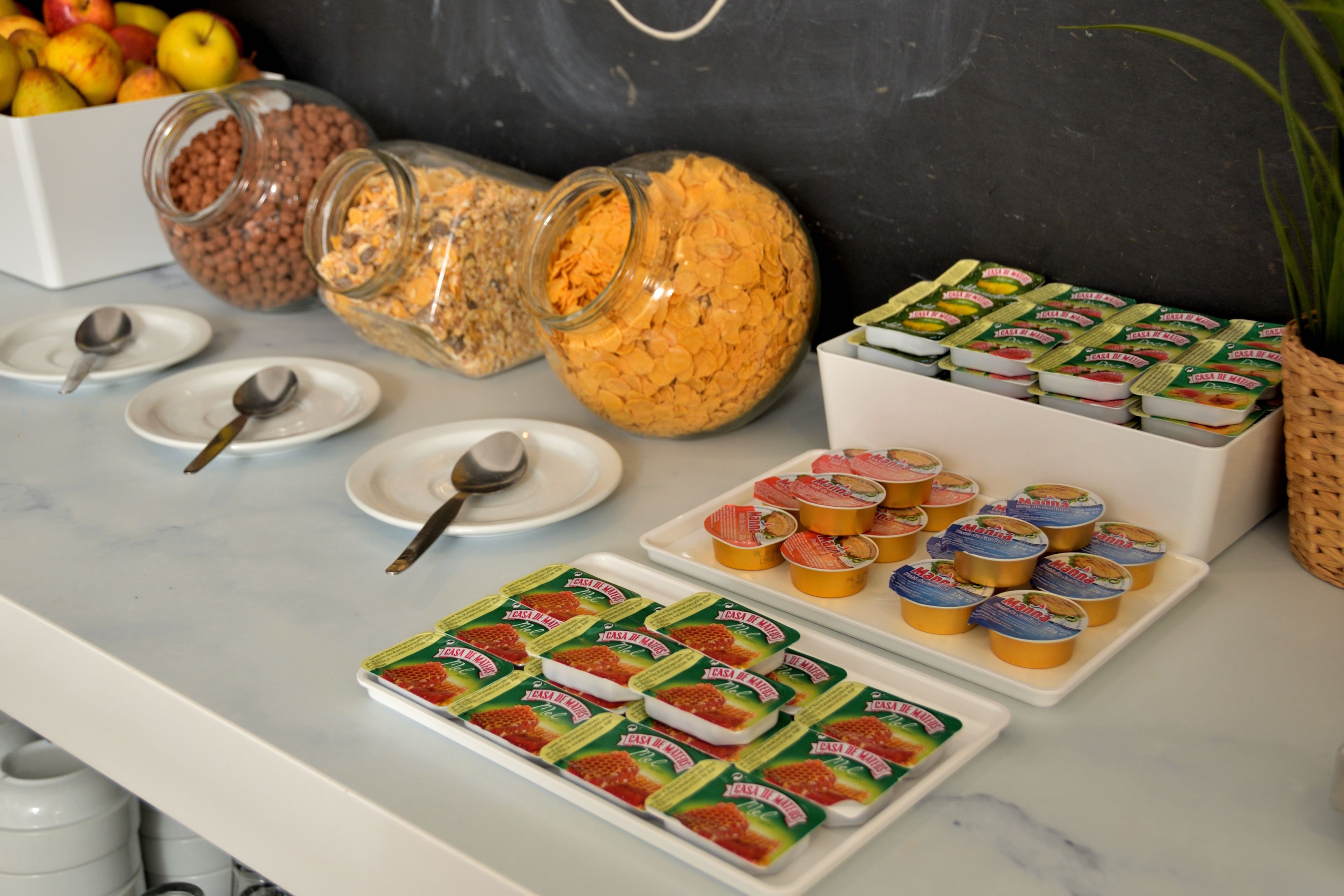 Een buffet met diverse etenswaren, waaronder potten met granola, cornflakes en verpakte snacks.