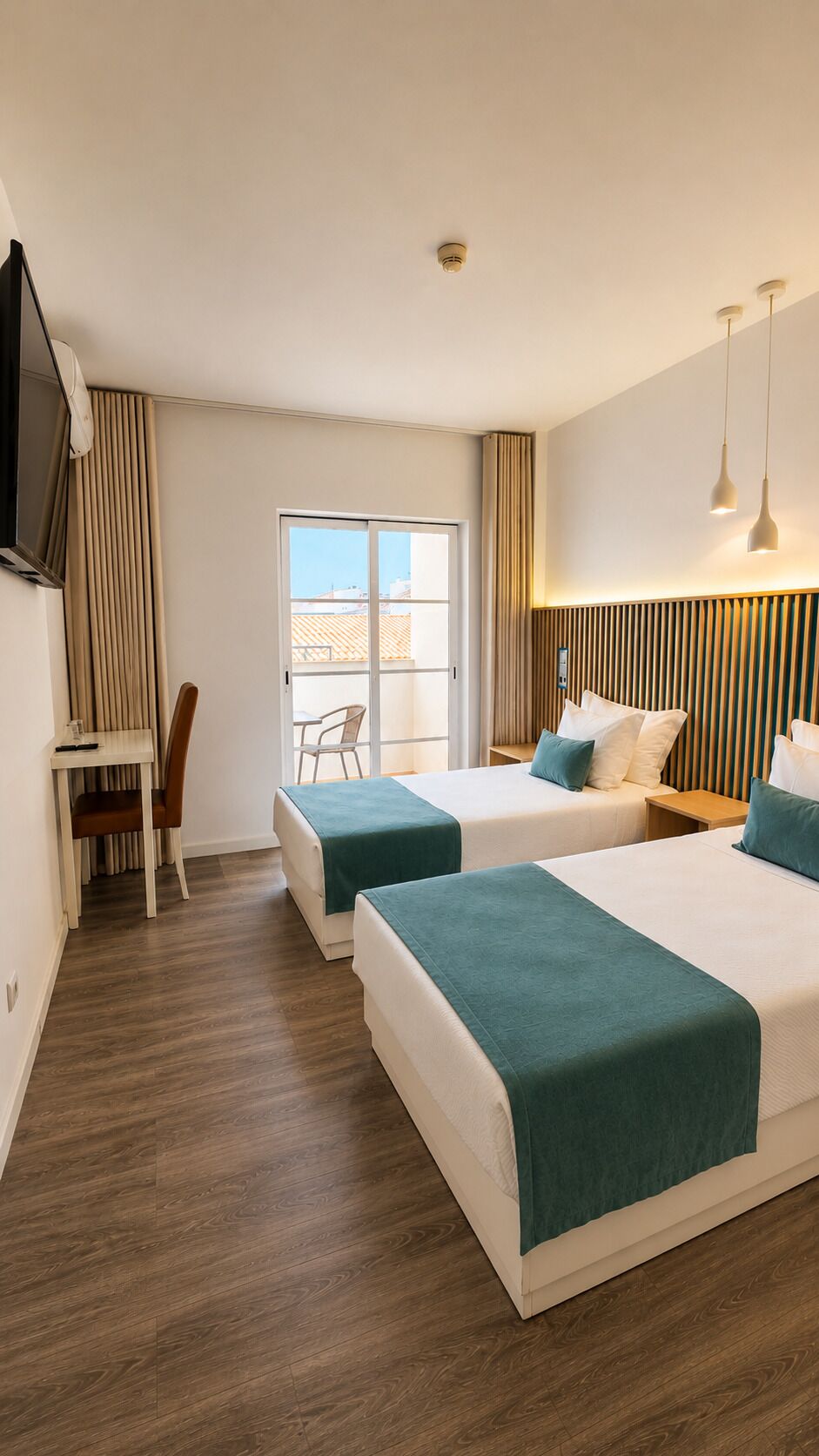 Een hotelkamer met twee bedden, een bureau, een stoel en een televisie.