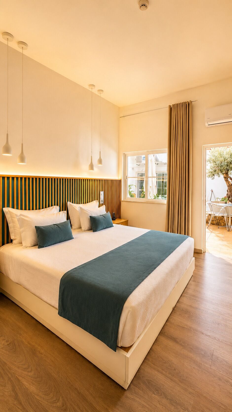 A modern hotel room with a large bed, bedside tables, a window with curtains, and a view of the outdoors.