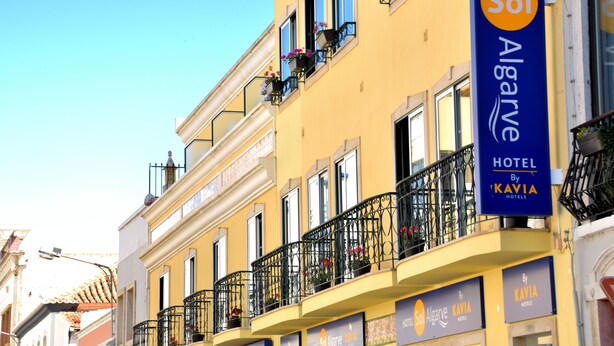 Un hotel con balcones decorados con jardineras, un cielo azul despejado y señalización que indica 'Sol Algarve Hotel by Kavia Hotels'.