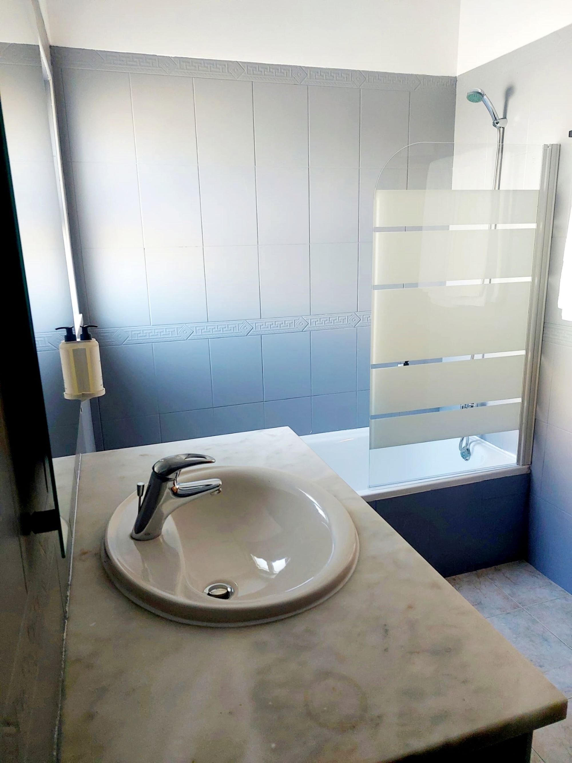 A bathroom with a sink, a shower, and a window.