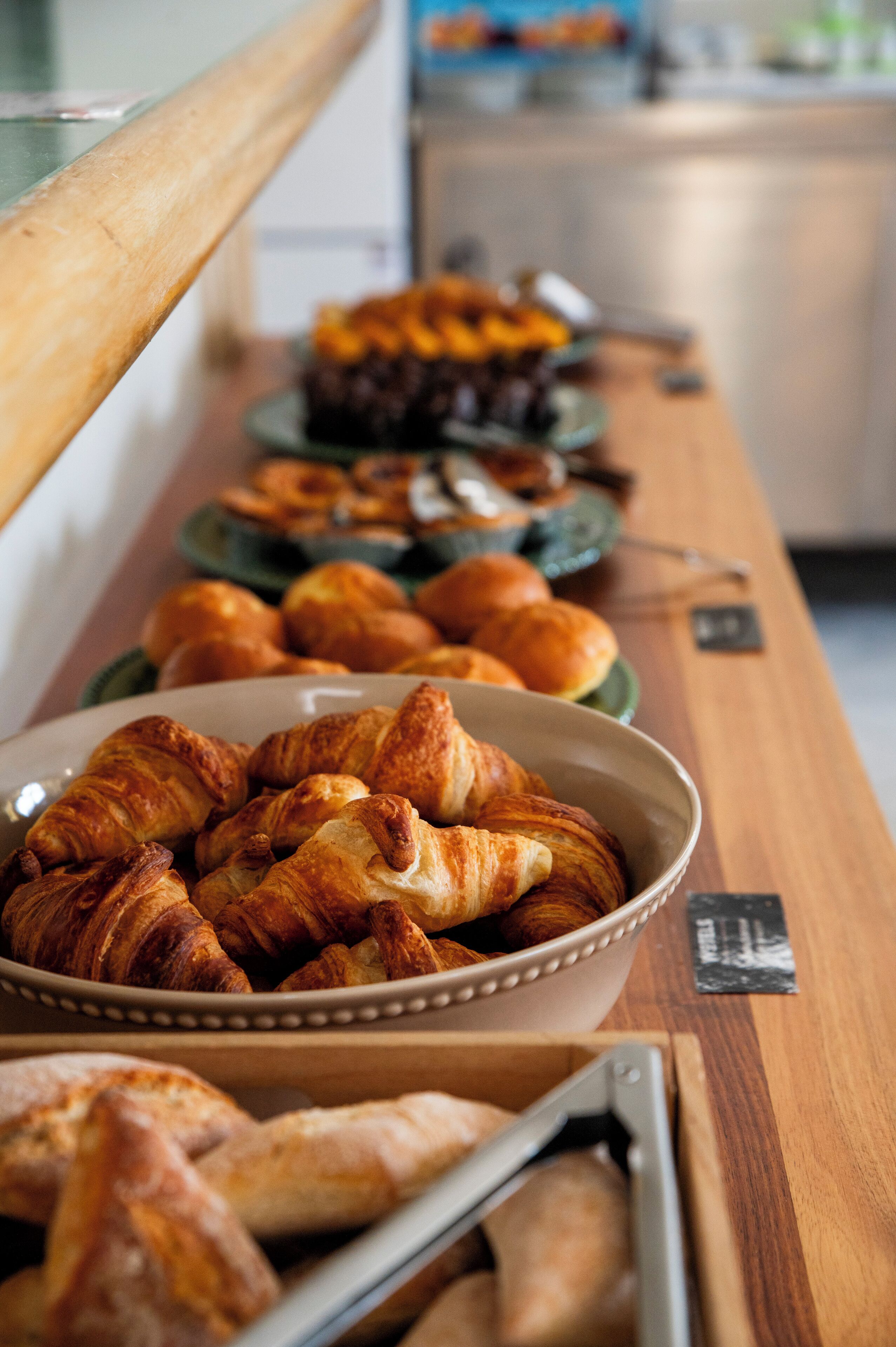 A buffet table with various baked goods, including croissants and bread rolls.