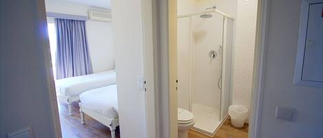 A bedroom with a bed, a bathroom with a shower, and a toilet.
