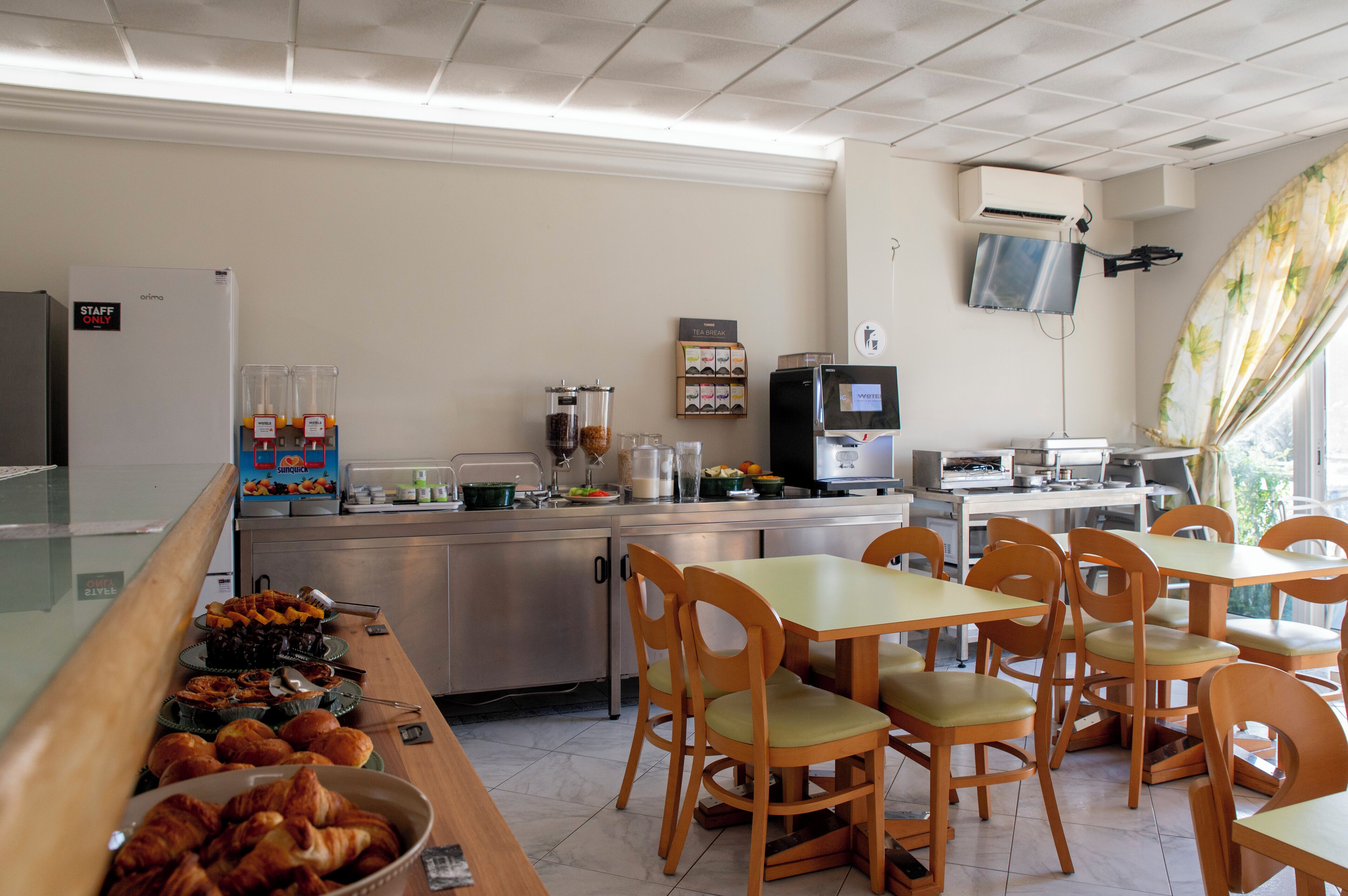 Un espace buffet pour le petit-déjeuner proposant une variété d’aliments, un coin café et des tables où s’asseoir.
