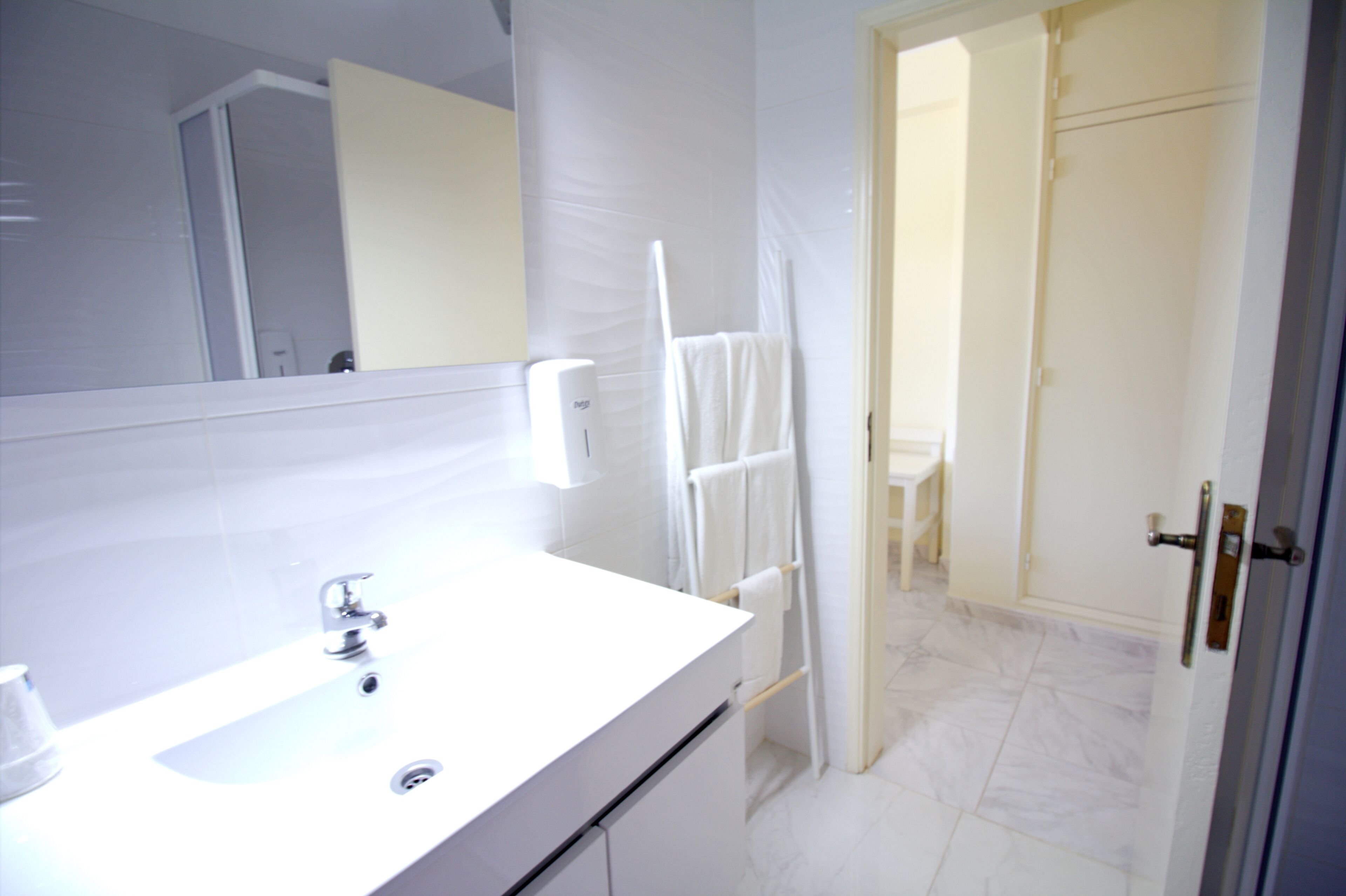 Ein Badezimmer mit Waschbecken, Spiegel und Handtuchhalter.
