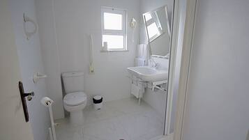 A bathroom with a toilet, sink, and a window.