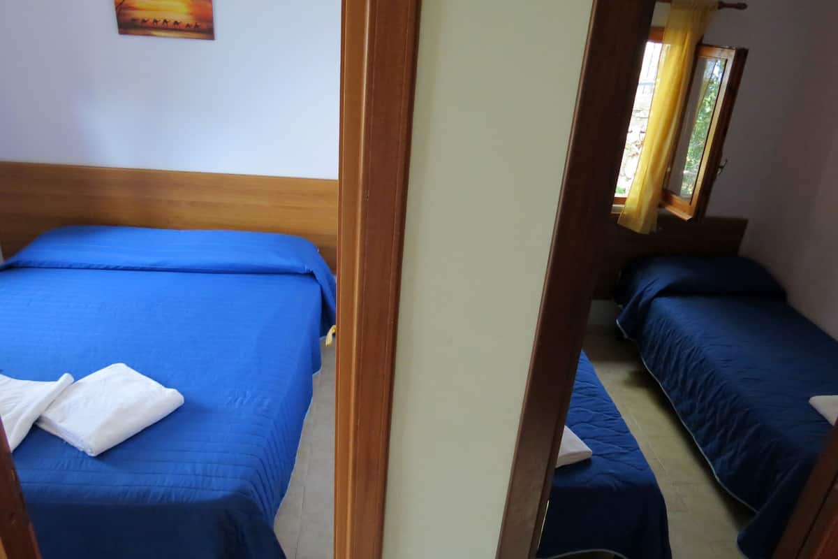 A room with two beds, each with blue bedding and white pillows.
