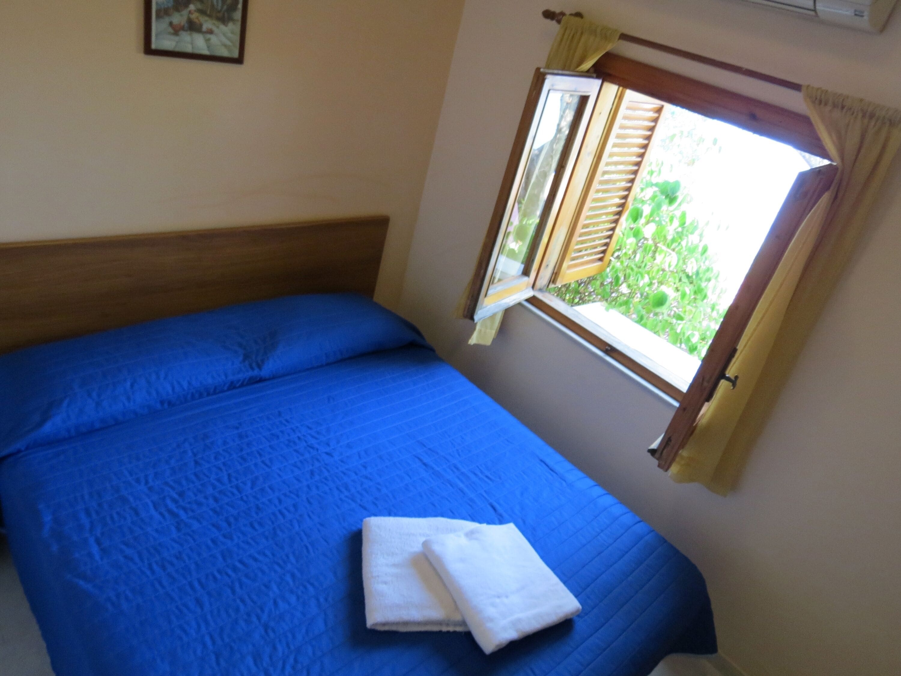 Un dormitorio con cama, ventana con cortinas y un equipo de aire acondicionado de pared.