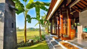 A modern house with a covered porch, a stone wall, and a well-maintained lawn. - Villa Kaba Kaba Resort Bali (Cepaka)