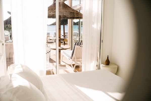 A hotel room with a bed, a view of the beach, and a table with chairs outside. - Hotel La Potinière (Hyères)