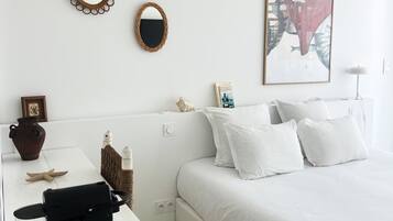 A neatly arranged bedroom with a bed, a bedside table with a tray, a mirror, and a framed picture on the wall.