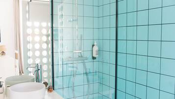 A bathroom with a glass shower enclosure, a white sink, and a mirror with lights.