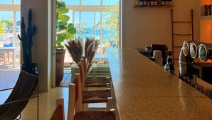 Una zona de bar con una barra larga, taburetes y vistas al exterior.