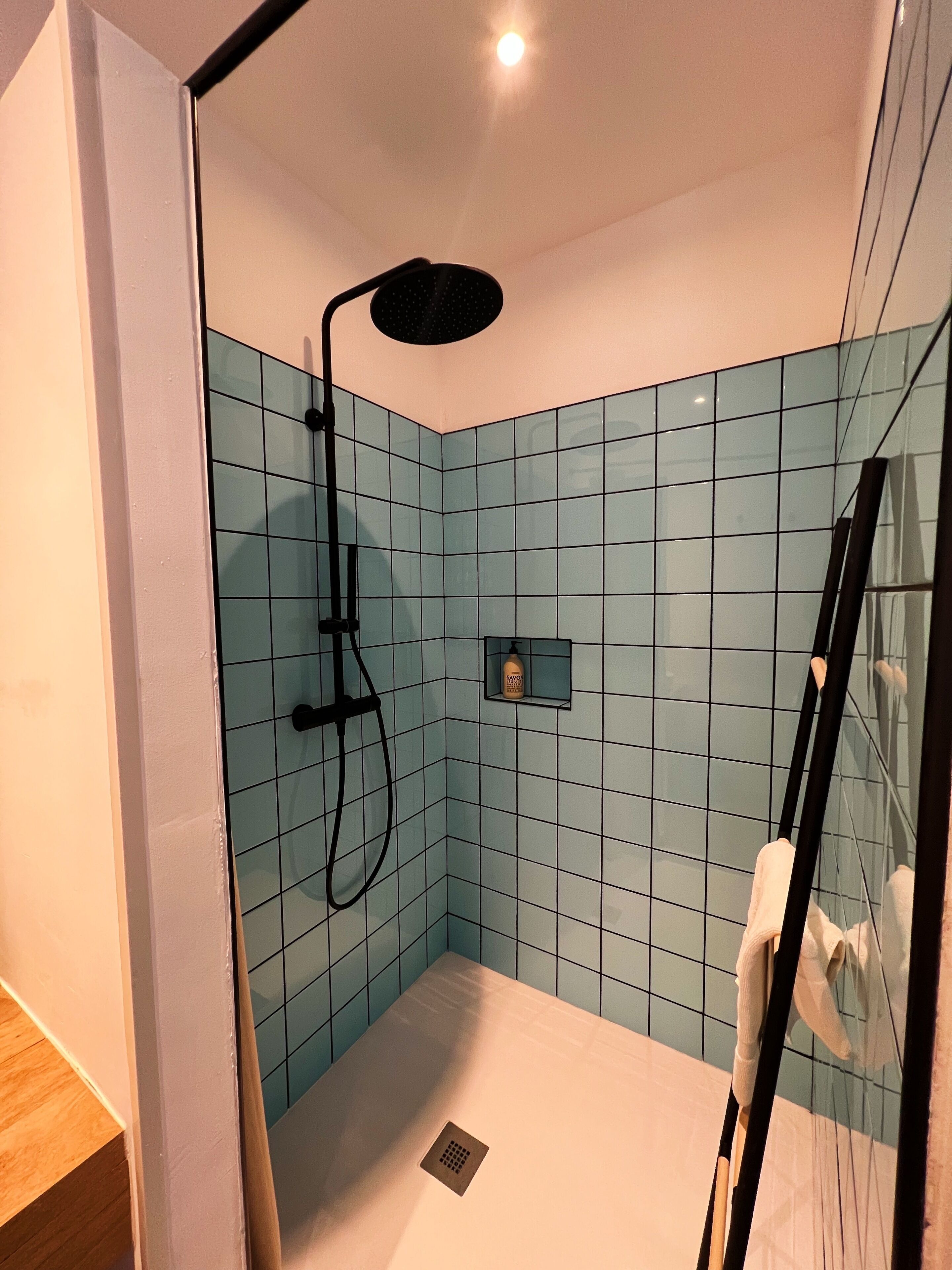 A small, modern bathroom with a shower, a handheld showerhead, and a glass-enclosed shower stall.