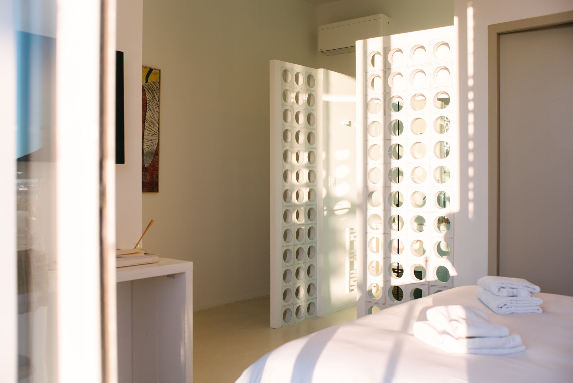 Habitación de hotel con cama, escritorio y puerta con diseños circulares.