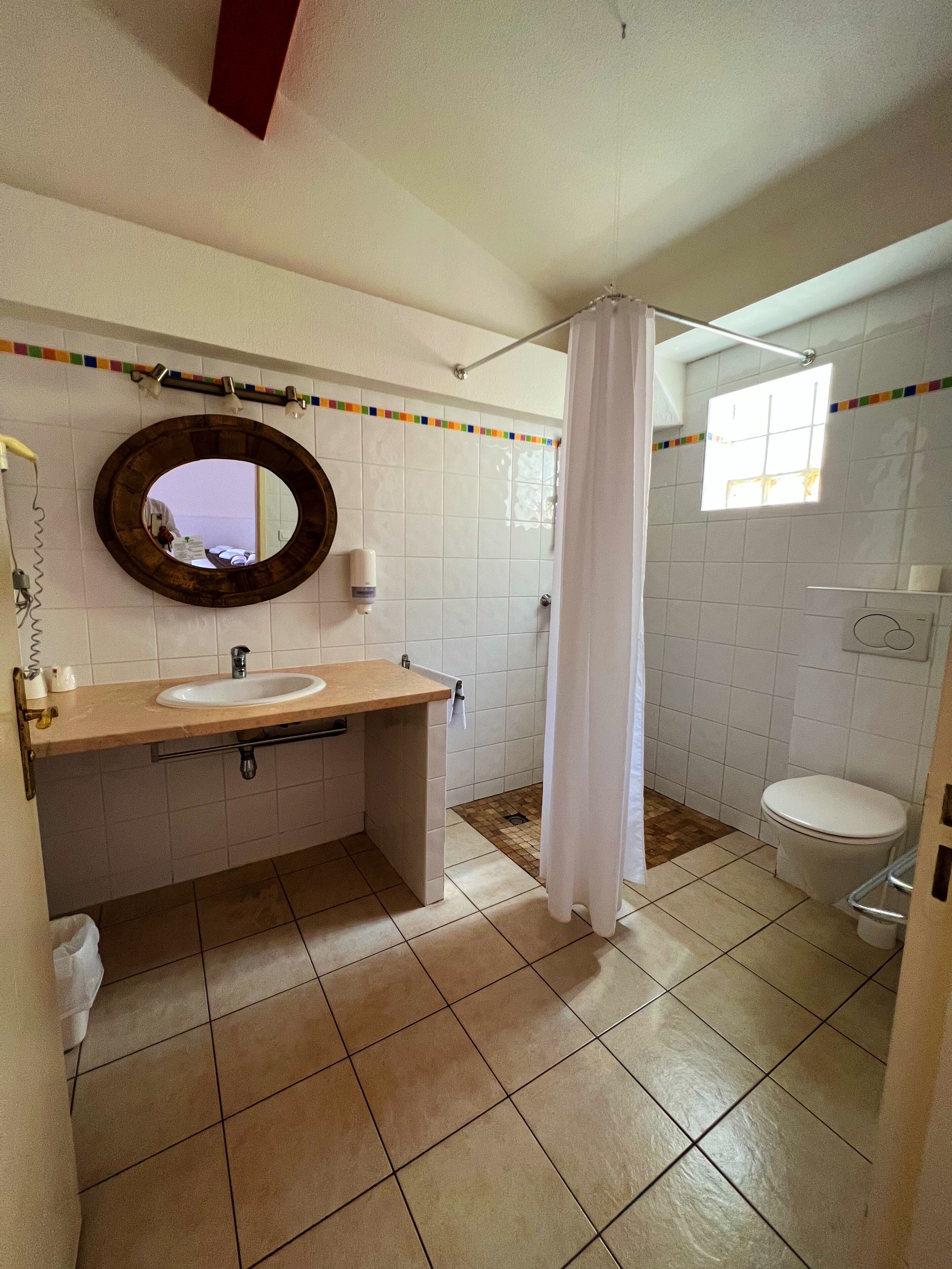 A bathroom with a sink, mirror, toilet, and shower curtain.