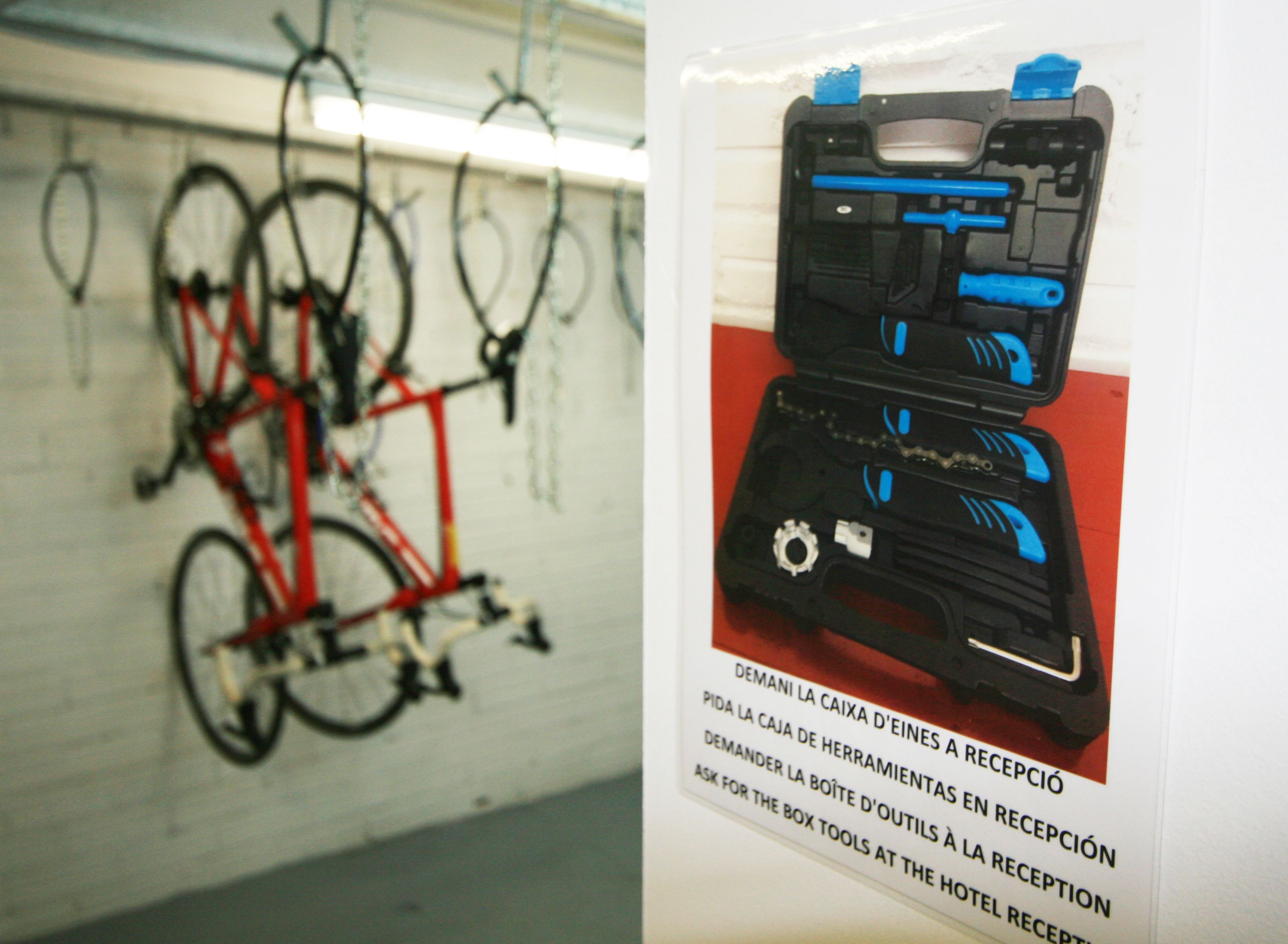 A bicycle leaning against a wall and a toolbox with a label in a foreign language.
