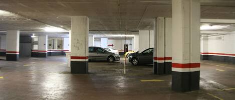 Un parking à plusieurs niveaux, avec des piliers en béton et des lignes de stationnement jaunes.