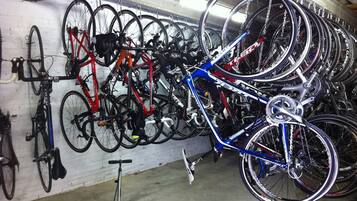 Un espacio para guardar bicicletas con varias bicicletas y un patinete.