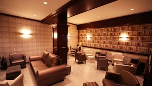 Un espace de détente moderne avec des canapés et des fauteuils en cuir, ainsi qu’une bibliothèque remplie de livres.
