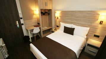 Une chambre d’hôtel avec un grand lit, un bureau avec une chaise, une armoire et deux lampes de chevet.