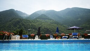 Une piscine entourée de montagnes, avec des chaises longues et des parasols.