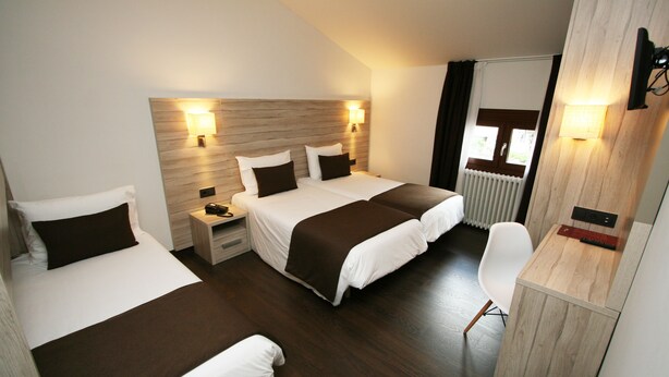 Une chambre d’hôtel avec deux lits, un bureau et une chaise.