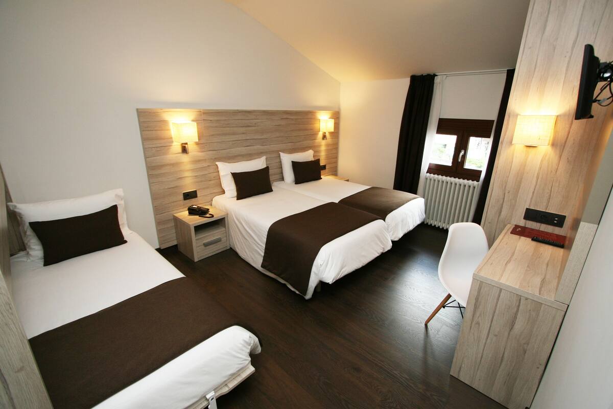 Ein Hotelzimmer mit zwei Betten, einem Schreibtisch und einem Stuhl.