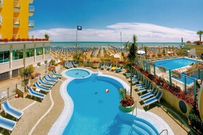 A resort pool area with multiple sun loungers and a central swimming pool. - Capri (Jesolo)