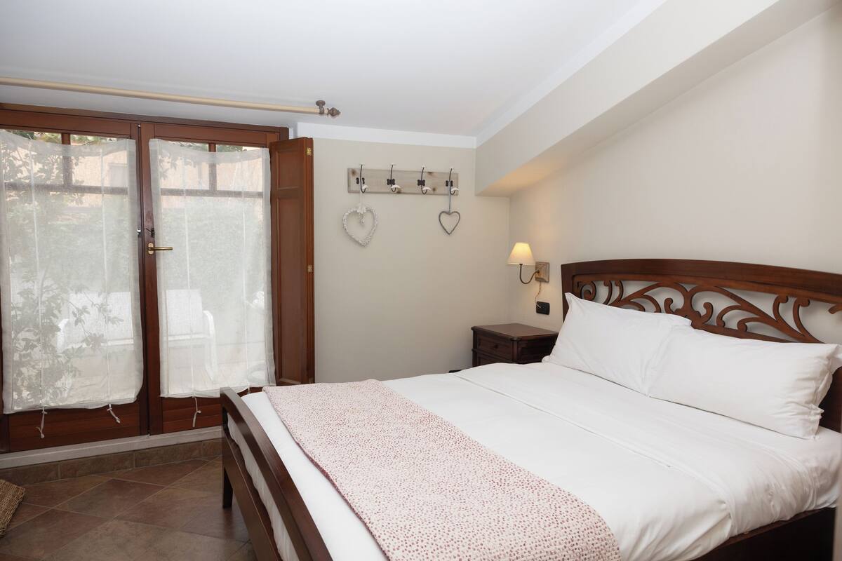 Un dormitorio con una cama de madera, una mesita de noche con lámpara y una repisa con adornos con forma de corazón.