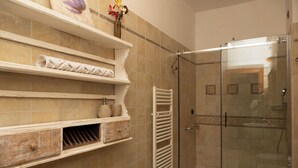 Un baño con cabina de ducha de vidrio, inodoro blanco y paredes con azulejos color beige.