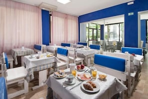 A dining area with tables set for breakfast, featuring plates of food, drinks, and a variety of breakfast items. - Holiday (Misano Adriatico)