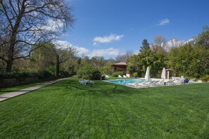 A well-maintained backyard with a swimming pool, lounge chairs, and a stone wall. - Le Verger Maelvi (Grimaud)