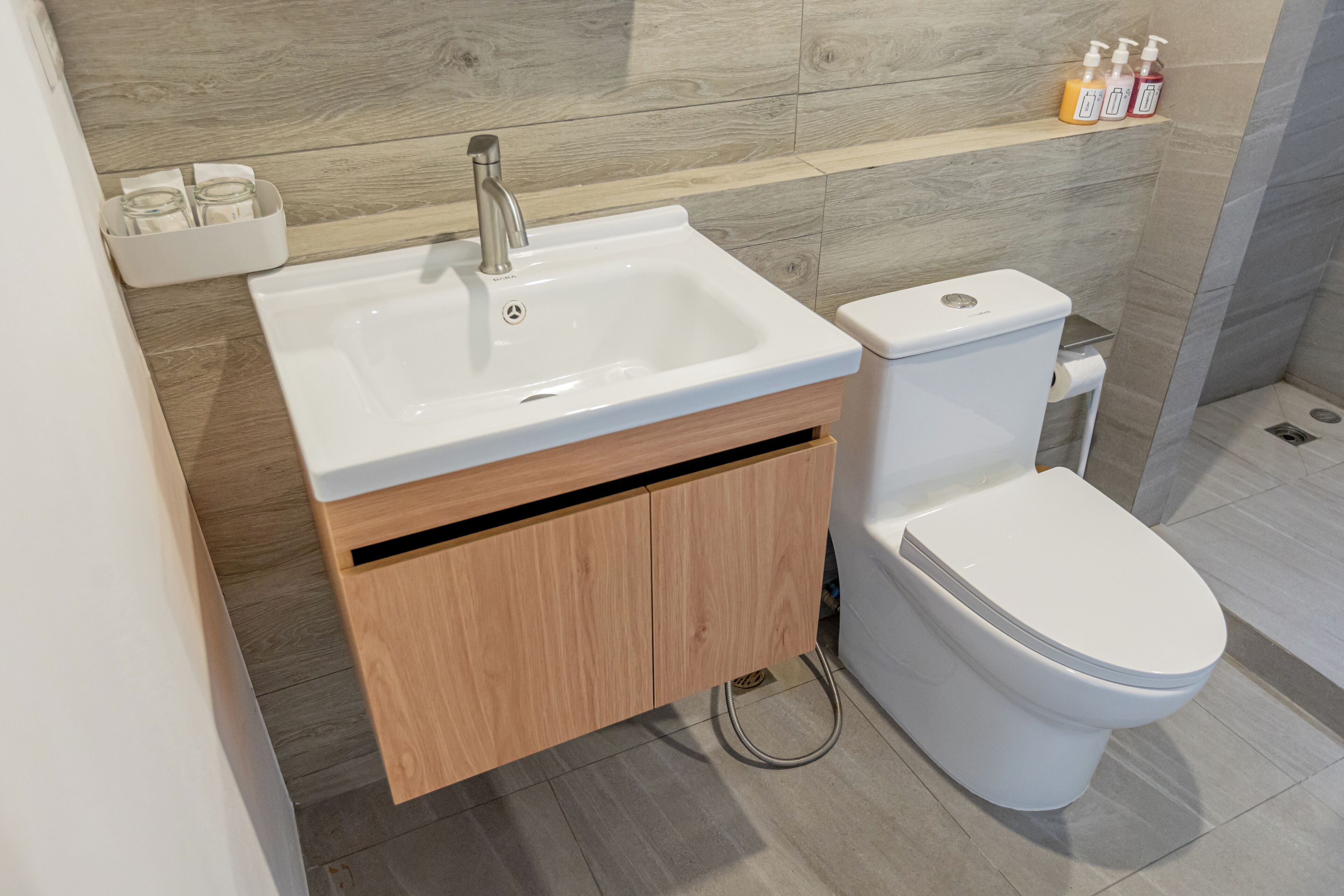 A modern bathroom with a white sink, wooden cabinet, and toilet.