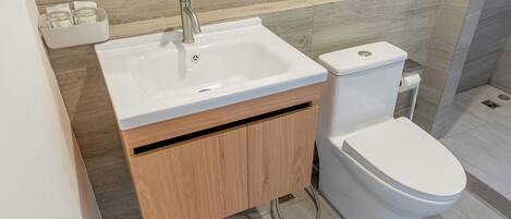 A modern bathroom with a white sink, wooden cabinet, and toilet.