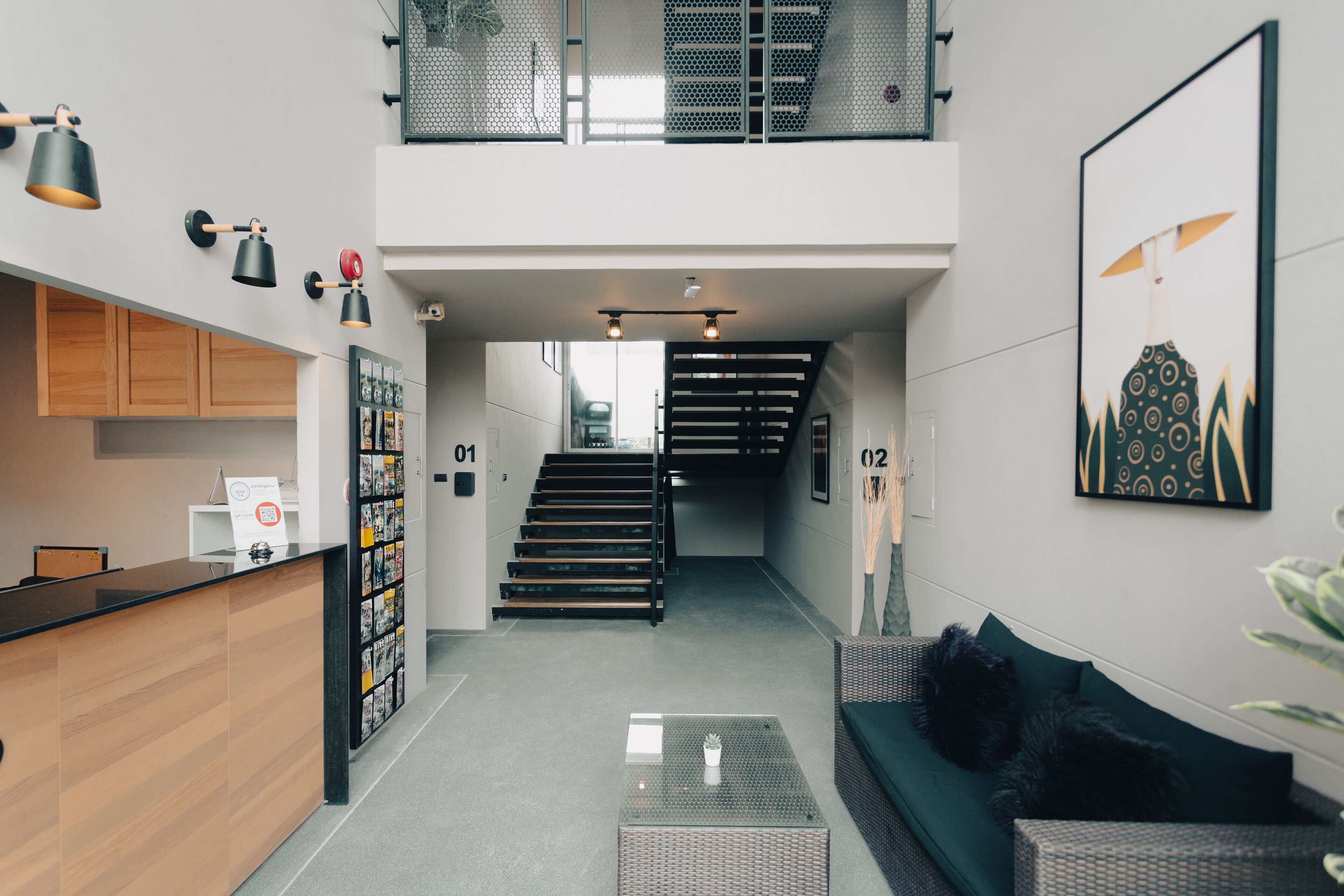 Un interior moderno con un mostrador de recepción, una escalera, una sala de estar con sofá y una obra de arte colgada en la pared.
