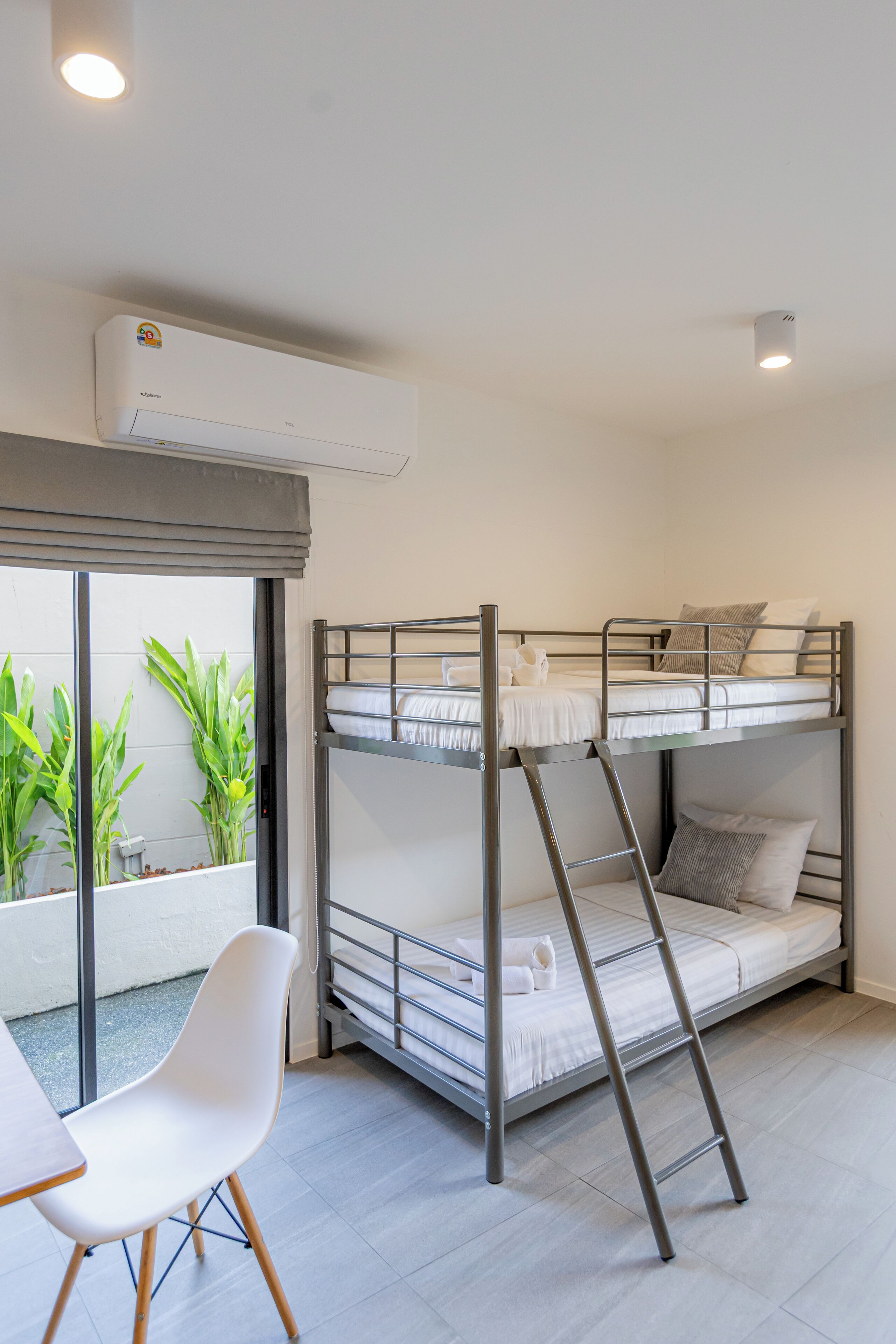 A bunk bed room with a ladder, a table, and a chair.