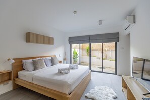 A modern bedroom with a large bed, a TV, and a sliding glass door to an outdoor area. - Studio365 Apartment (Chiang Mai)