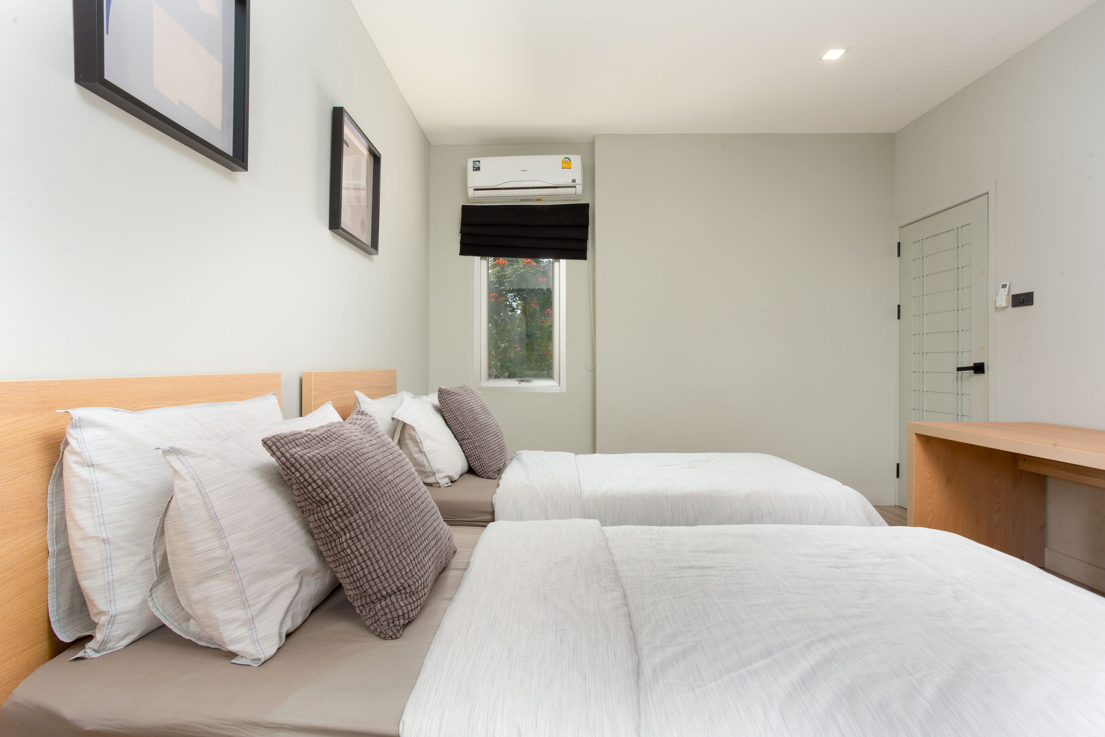 Une chambre d’hôtel avec deux lits, une fenêtre donnant sur un beau paysage, un appareil de climatisation et un bureau en bois.